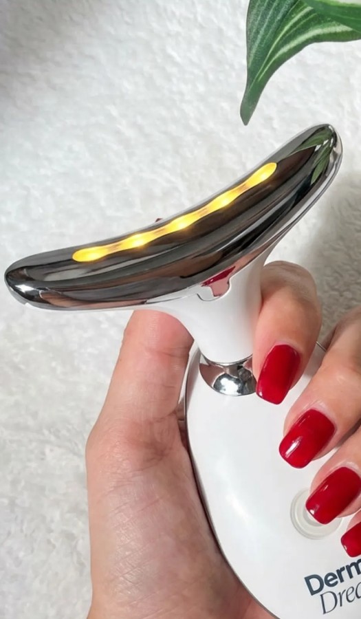 MyoGlow handheld skin device held in a hand, chrome head with warm LED lights glowing