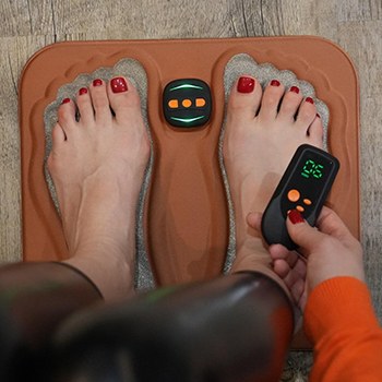 Close up of the NeuroMat pad showing the textured foot areas and the control unit